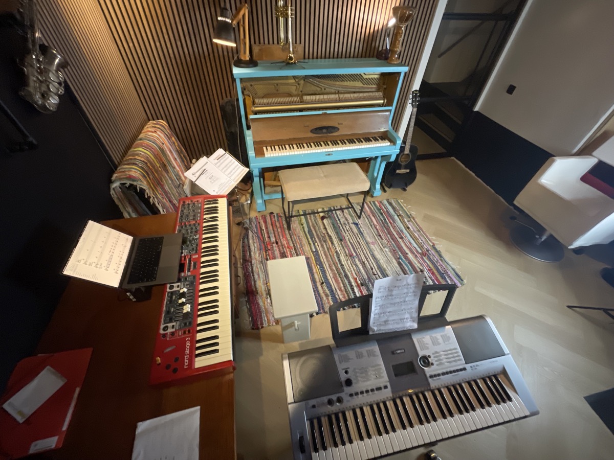 De lesruimte van bovenaf, met piano en beide keyboards